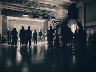 Behind the scenes of music video shooting production crew team silhouette and camera equipment in studio. Black and White.