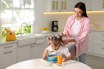 Sticker - Young mother helping her little child get ready for school in kitchen