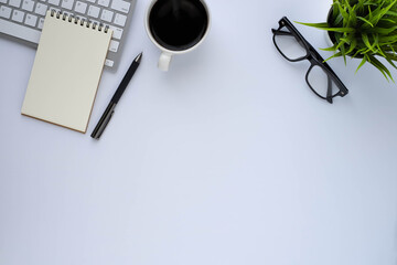 Top view above of White office desk table with keyboard computer, notebook and coffee cup with equipment other office supplies. Business and finance concept. Workplace, Flat lay with blank copy space.