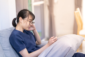 Young asian woman use smart mobile phone on sofa in living room interior