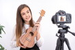 © Enrique Micaelo  - Young woman with guitar creating online content on white background with copy space