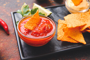 Tasty nachos with salsa sauce on grunge background, closeup