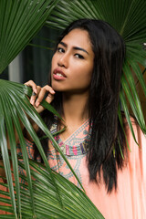 Wall Mural - Close up portrait of beautiful thai woman over tropical  leaves background. Spa and relax concept.