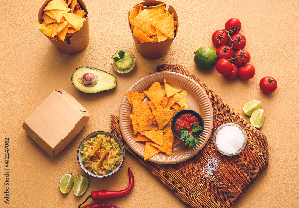 Plate with tasty nachos and sauces on color background