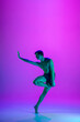 © master1305 - Performing. Young and graceful ballet dancer on purple studio background in neon light. Art, motion, action, flexibility, inspiration concept. Flexible caucasian ballet dancer, moves in glow.