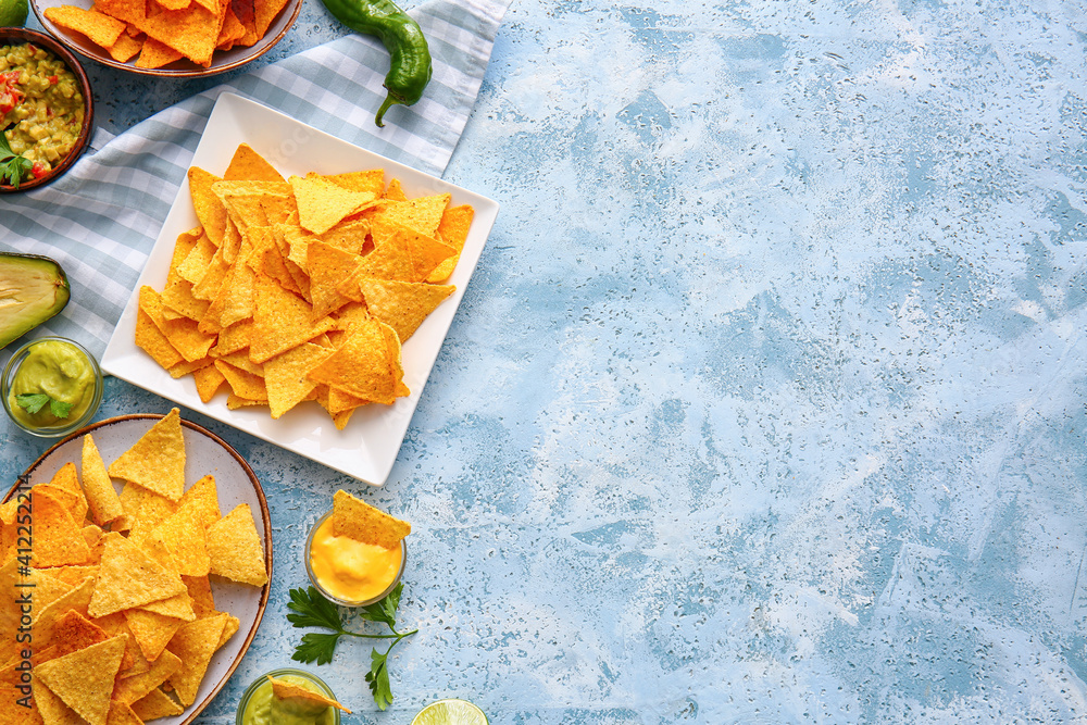 Plates with tasty nachos and sauces on color background