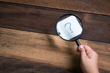 Cropped Image Of Hand Holding Magnifying Glass On Question Mark