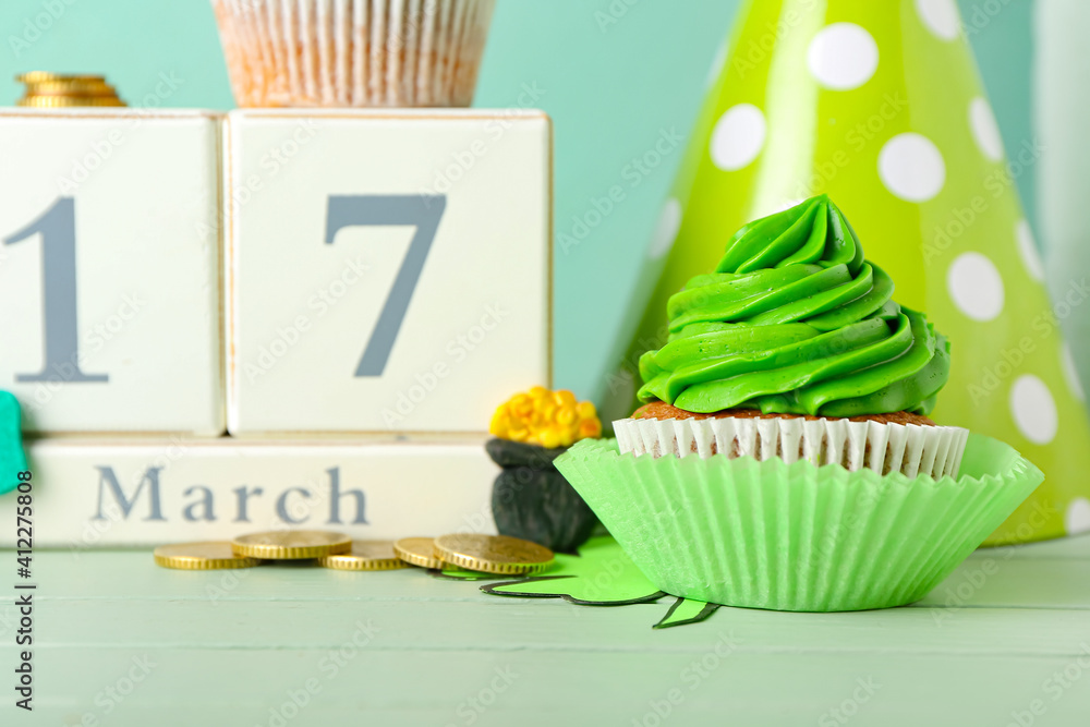 Tasty cupcake for St. Patrick's Day and calendar on table