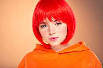 Closeup portrait of an young  girl with a red hair over colored background. Pretty teen girl with  freckles on face. Beauty portrait.    Photo of a young fashion model in orange clothes.