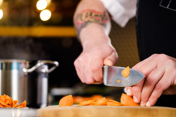 Wall Mural - The cook cuts vegetables, peppers, onions and carrots on a chopping board