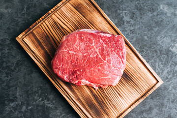 Wall Mural - Raw beef steak on wooden board and black background.