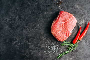 Wall Mural - Raw beef steak on black background with rosemary, chili pepper and spices, copy space.