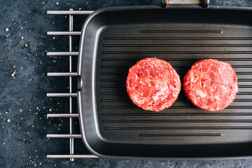 Wall Mural - Fresh raw minced beef steak for burgers on black grill pan.