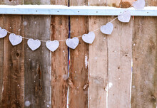 Garland Of Purple Wooden Hearts On Dark Wooden Fence Background, Valentine's Day Greeting Card