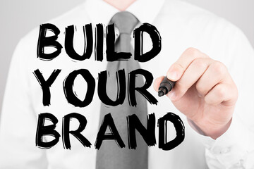 Wall Mural - businessman writing word build your brand with marker, business concept
