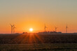 Wind turbines spin in the early morning light, with small family farms in the background. Concepts of the environment, green energy, and the Midwest