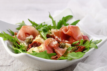 Wall Mural -  Arugula salad, prosciutto with sun-dried tomatoes, slices of mozzarella, capers, seasoned with olive butter and parmesan. A dish for those who monitor their health