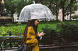 © simon/Stocksy - Young woman using a phone under the umbrella