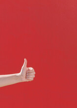 Thumb Up Hand Against A Red Wall
