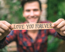 Young Man In Love Holding Love You Forever Message.