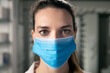 Cinematic close up shot of female pharmacist consultant with medical protective mask is looking in camera in pharmacy. Concept of covid-19, protection, coronavirus, prevention, safety, health care.