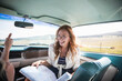 © Robinson Media Inc/Stocksy - Happy woman in Vintage car giving directions on a map