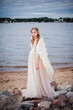 © Kseniia Ovsiankina - A sweet tender bride with angel wings stands on the shore of the bay.