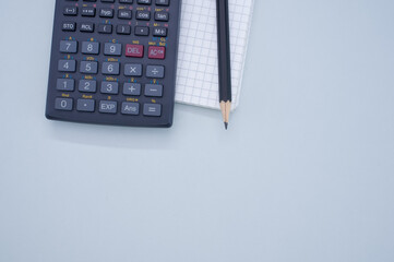 top view of a scientific calculator, paper, and pencil isolated on gray background