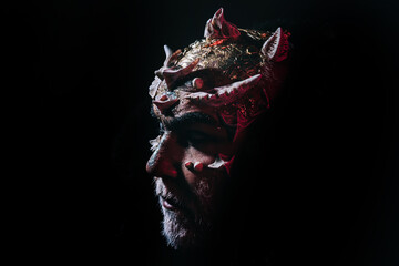 Devil demon, sorcerer makeup. Horror and fantasy concept. Man with thorns or warts. Demon on black background, copy space. Senior man with white beard dressed like monster in darkness.