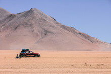 Car On Desert With Mountain On The Background. SUV 4WD Vehicle, Bolivia