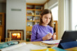 © MNStudio - Preteen schoolgirl doing her homework with digital tablet at home. Child using gadgets to study. Education and distance learning for kids. Homeschooling during quarantine.