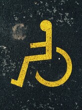 Yellow Parking Space For Disabled Sign On Black Asphalt