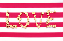 Word Love From Wodden Hearts On Red White Striped Background
