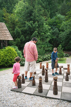 Family Playing Chess On A Giant Board Outdoors