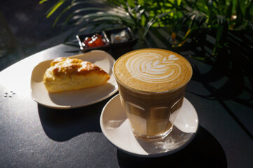 Close up hot cappuccino with heart shape latte art and Homemade Scone with Jam and Cream on dark  table at caff food and drink concept.