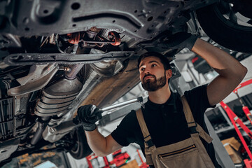 Mechanic examining under the car at the repair garage.