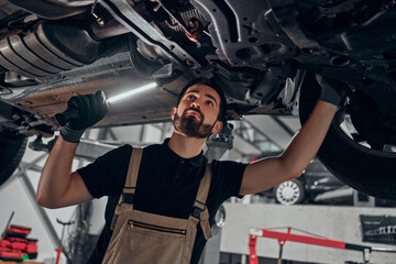 Professional auto mechanic working on the undercarriage of a car.