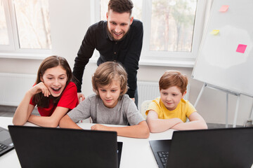 Wall Mural - teacher and children using laptop during lesson