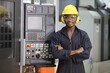 © Akarawut - Portrait of African American mechanic engineer worker wearing safety equipment beside the automatic cnc lathe machine in manufacturing factory