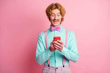 Poster - Photo of young happy smiling positive amazed shocked gentleman using cellphone isolated on pink color background