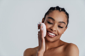 Wall Mural - Joyful shirtless african american woman using powder sponge