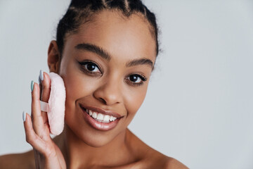 Wall Mural - Joyful shirtless african american woman using powder sponge