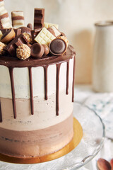 Poster - Vertical shot of chocolate ombre naked cake with sweets and chocolate drip on glass cake stand