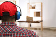 © New Africa - Worker wearing safety headphones indoors, back view. Hearing protection device