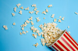 Fototapeta Tęcza - the popcorn cup fell on its side and the popcorn spilled out on a blue background