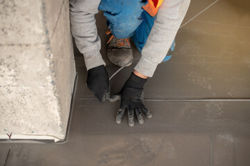 Worker working on the floor of an industrial building. Construction worker producing grout and finishing wet concrete floor.