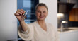 © nimito - Portrait of smiling senior woman showing keys to new house at camera