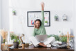 © LIGHTFIELD STUDIOS - excited african american architect looking at camera while sitting on desk with laptop and raised hand