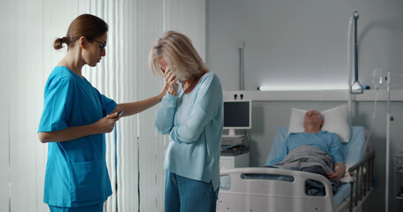 Doctor telling bad news to aged male patient wife in hospital