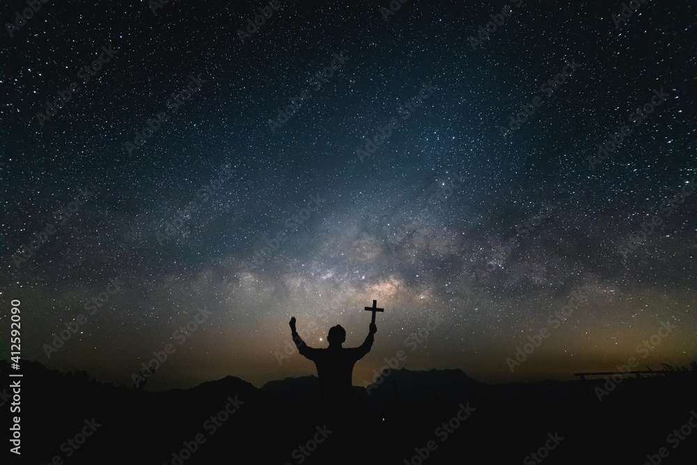Silhouette Human praying and holding christian cross for worshipping God at Night landscape with colorful Milky Way. - obrazy, fototapety, plakaty 